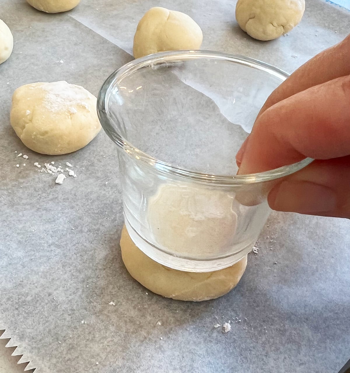 flattening cream cheese cookies with a small glass